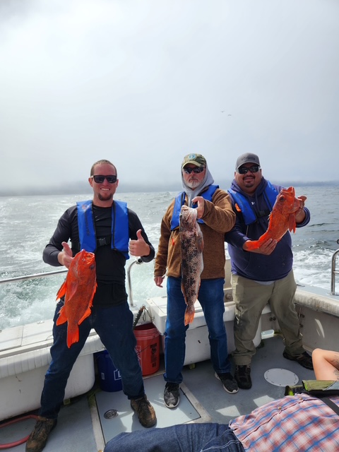 Three veterans showing off rockfish catch on the boat