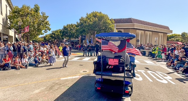 MBV shuttle leading parade with crowds and American flags