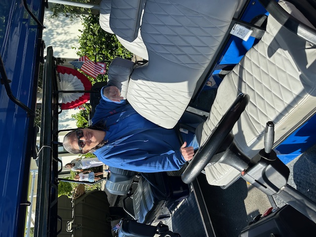 MBV volunteer driver in blue shuttle with American flag